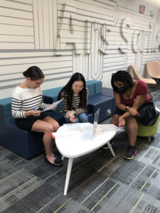 Three students from the Spring 2023 EPIC learning community sit around a table and work together at an activity during the meeting.