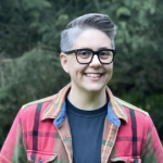 Smiling woman with glasses and a flannel shirt