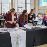 Three women standing at a table with a CTL logo on it